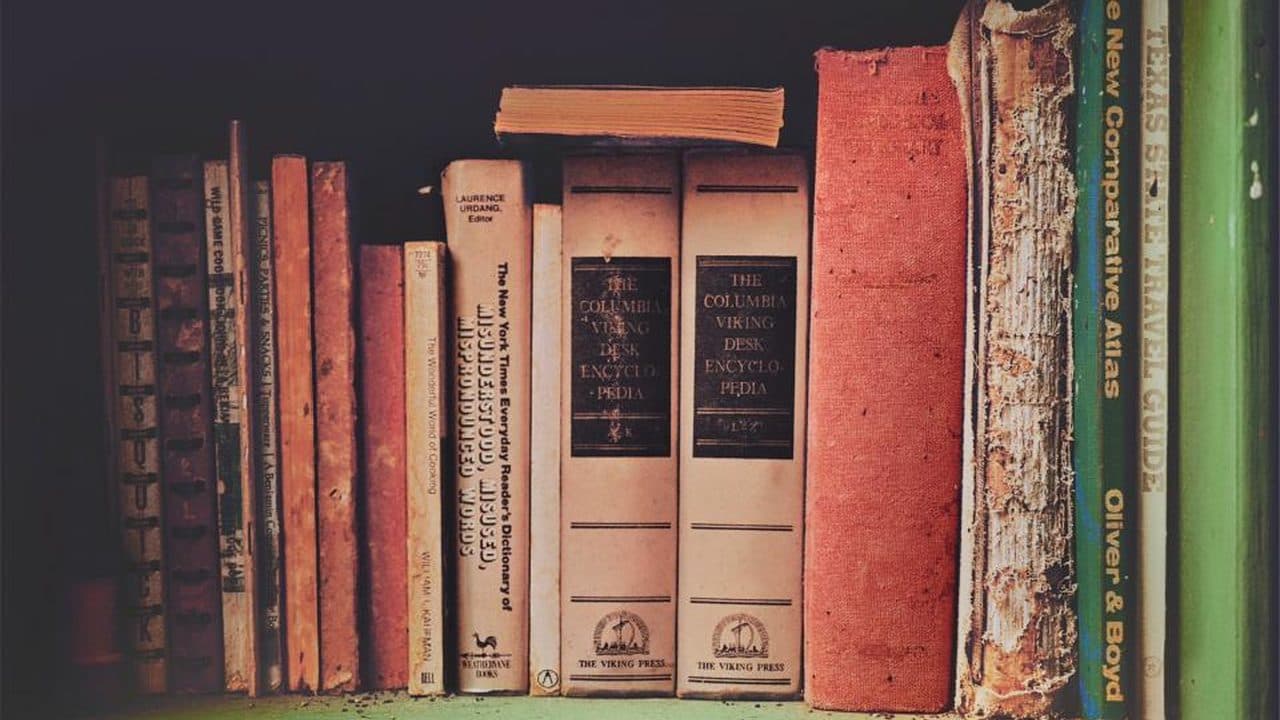 A shelf of worn vintage hardbacks, two of them Columbia Viking Desk Encyclopedia volumes